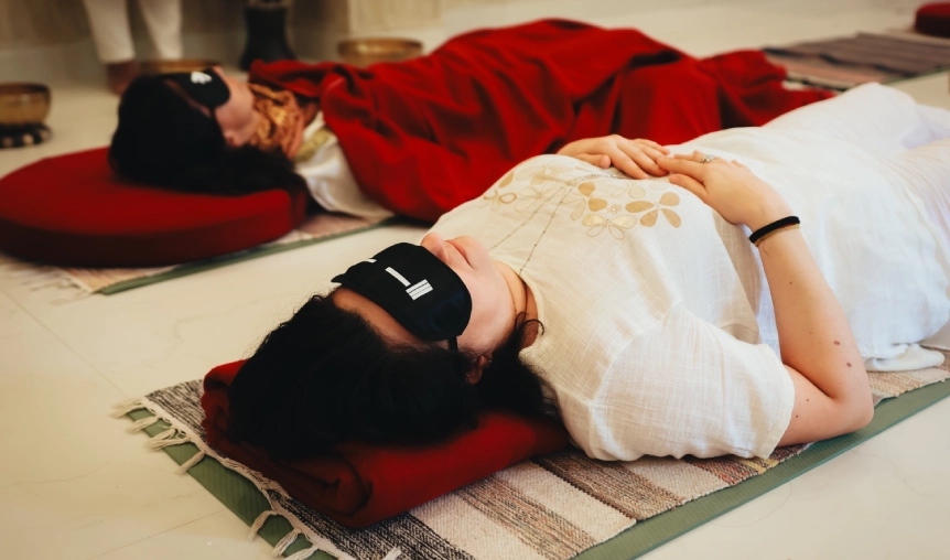 Instructor demonstrating singing bowl healing technique on student during sound therapy training