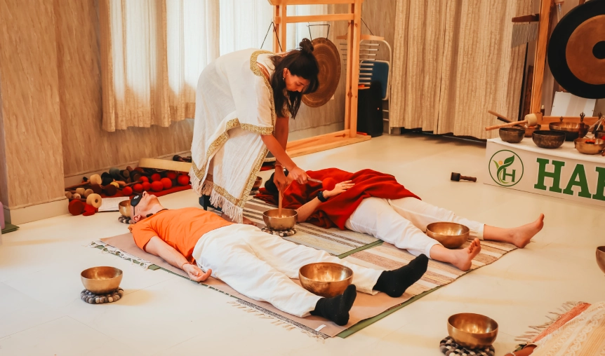 Teacher conducting singing bowl sound healing session for students lying in relaxation