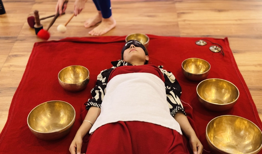 Student practicing singing bowl placement therapy on partner during teacher training